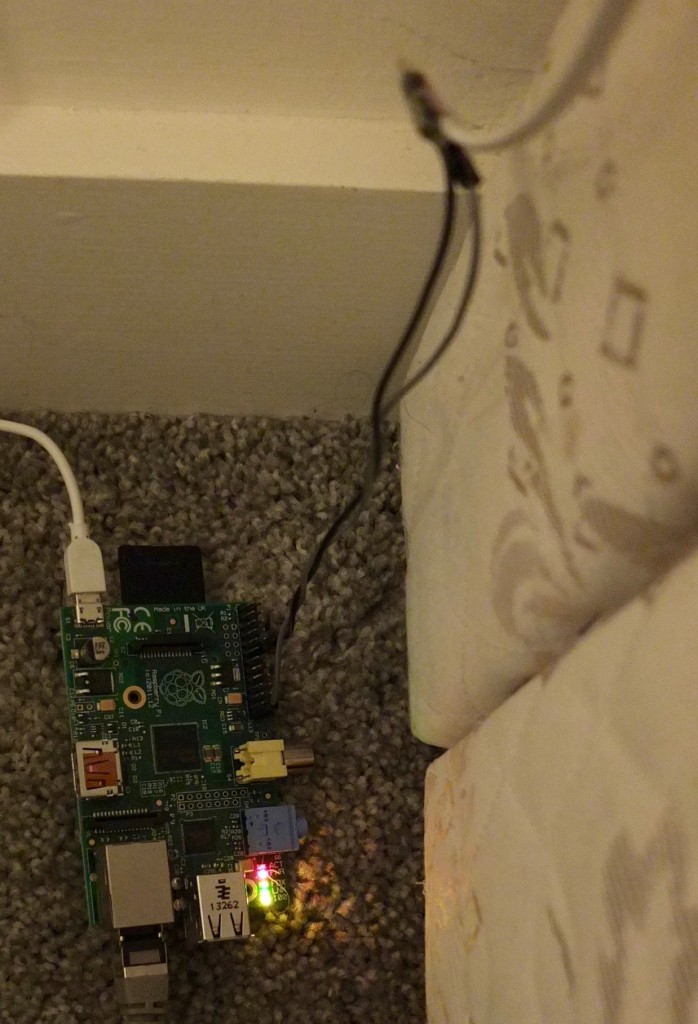 The Raspberry Pi beside the bed, with wires from the pressure mat connected to GND and GPIO pin 18 via an old telephone cable