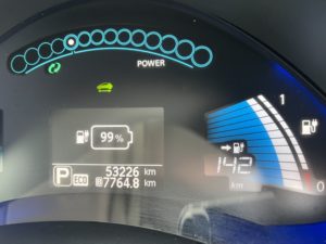 Dashboard of a Nissan Leaf, showing 99% battery charge, 142km indicated range, and 12/12 battery health indicators